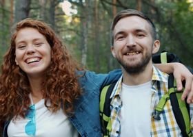 Two friends smiling during a forest hike, enjoying nature and friendship.